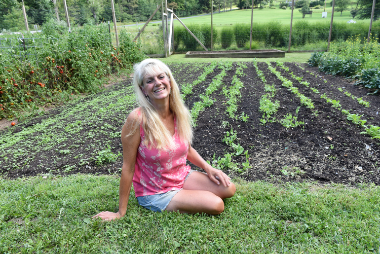 Karin Eller, owner of Plant-It Earth Greenhouse near Homer City, sits in front of the garden filled with fall crops.