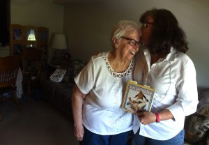 Dorothy Shillingburg gets a kiss from her neice Amy Wilkinson who is holding Herman Wigle's journal. He was Shillinburg's father and Wilkinson's grandfather. He was instrumental in teaching both about gardening and life.