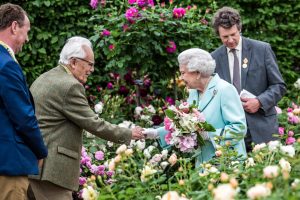 Britain's Queen Elizabeth II is greeted by David C. H. Austin, both then 90 years old, at the David Austin Roses garden at the 2016 Chelsea Flower Show in London on May 23, 2016. Behind Mr. Austin is his son David J. C. Austin, managing director of David Austin Roses.